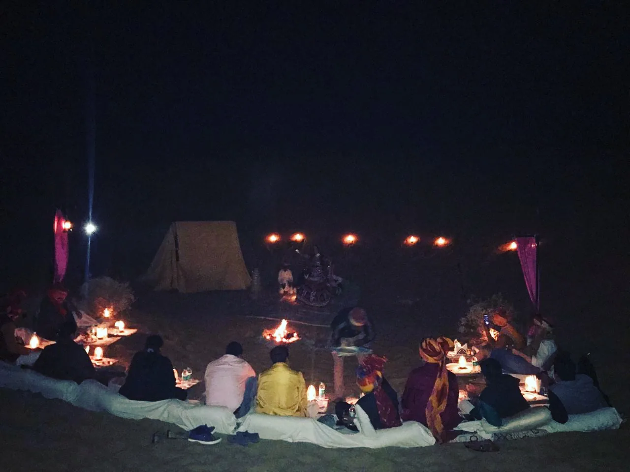 Dinner laid out on rugs at the desert camp under strung lights